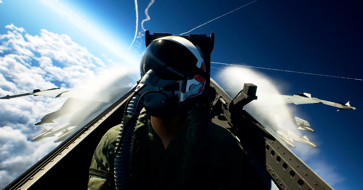 A pilot in a white and red flight helmet in a fighter jet cockpit, wing missiles and vapor trails against the clouds in Ace Combat 8