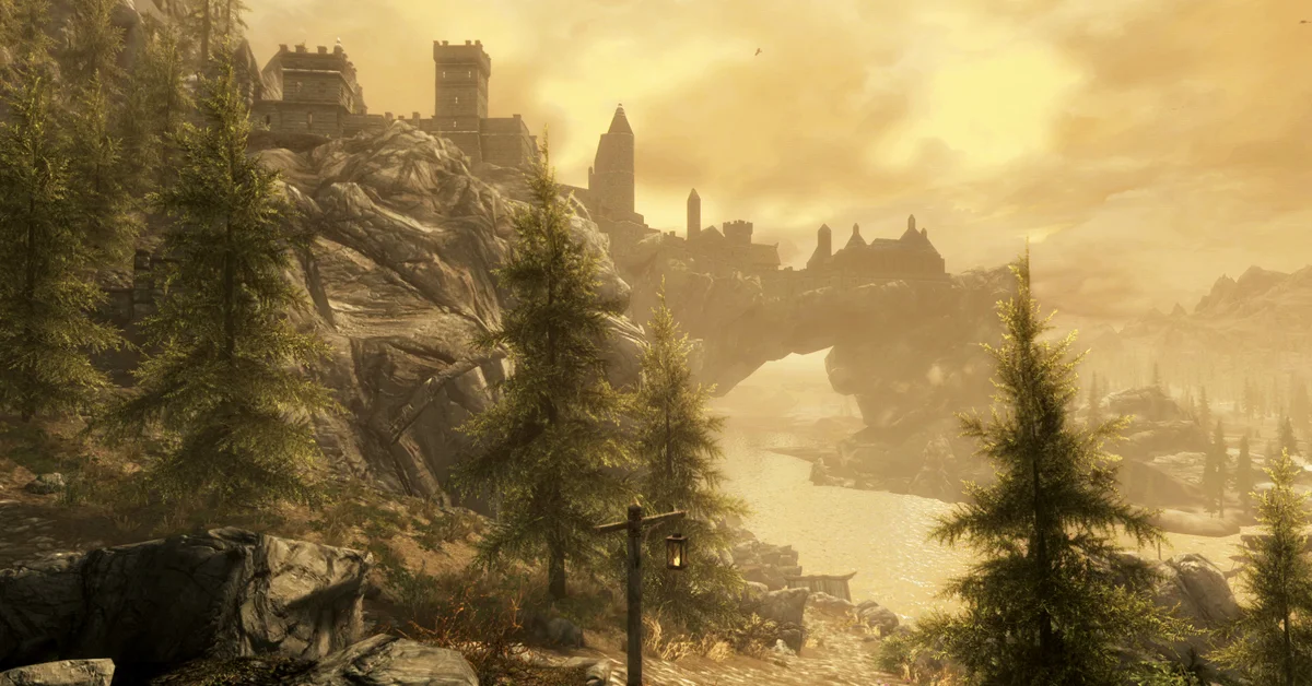 The walled city of Solitude with its towers perched on a huge natural stone arch above a river at golden hour in Skyrim