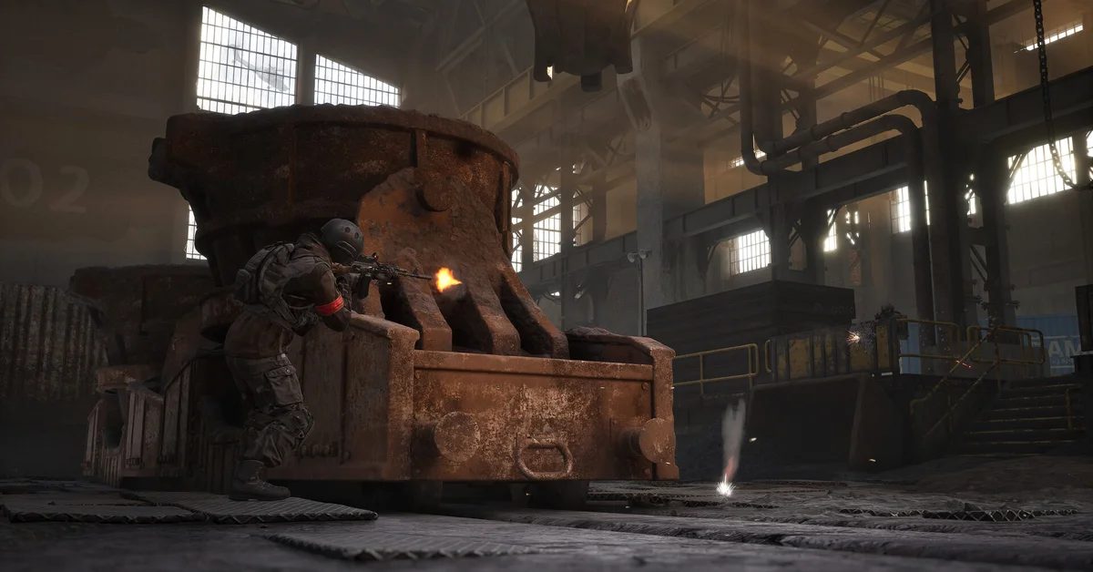 A WARDOGS soldier takes cover behind a rusted steel cauldron inside an abandoned factory