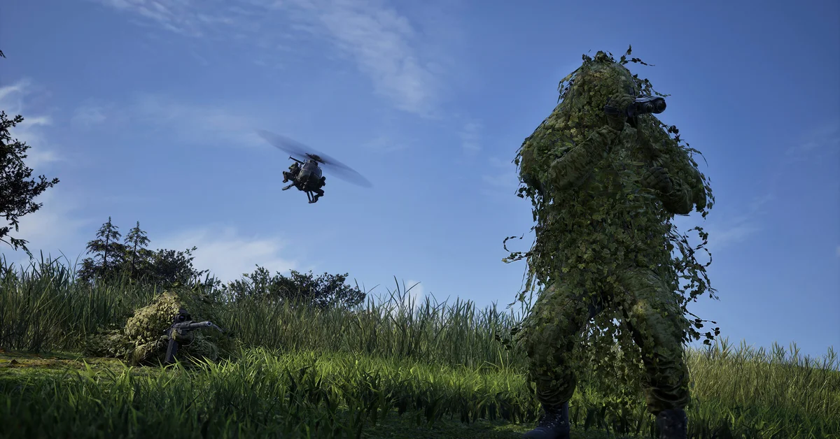 A WARDOGS sniper in a ghillie suit stands in tall grass as a helicopter flies overhead