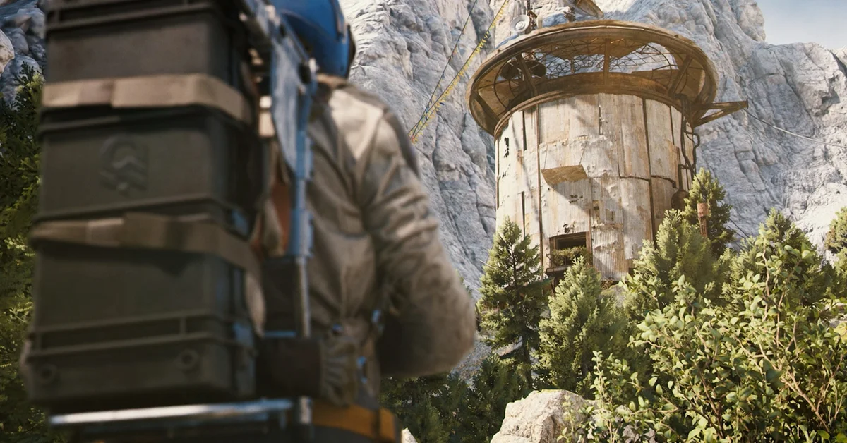 A raider with a stacked backpack looks up at the Outpost tower on a rocky mountainside in ARC Raiders Frozen Trail