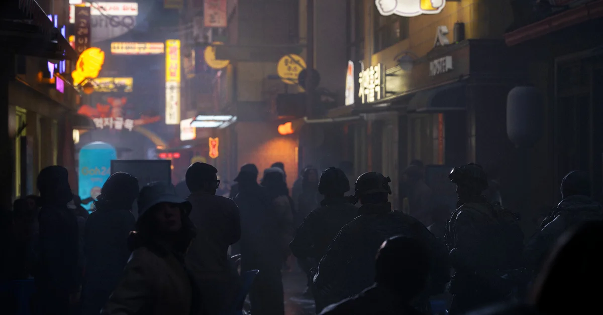 Soldiers moving through a crowded neon-lit street at night in Call of Duty Modern Warfare 4