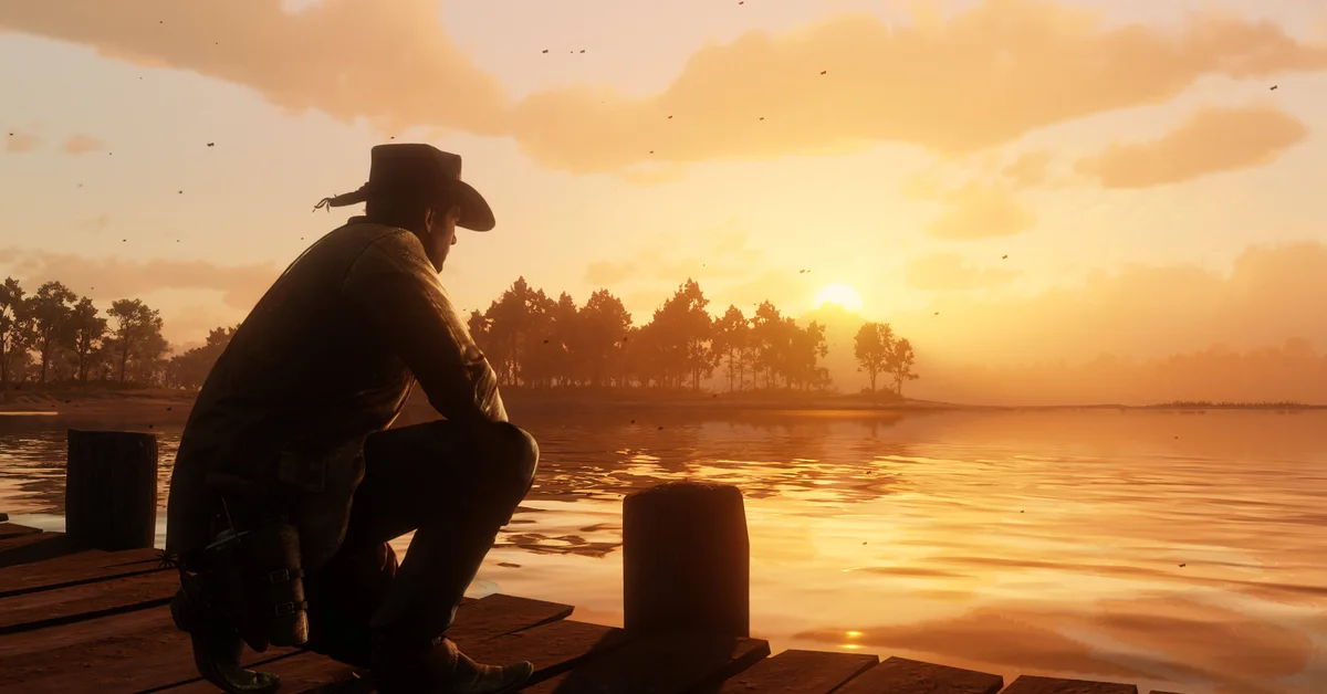 Arthur Morgan crouched at the end of a wooden dock looking out over a lake at sunset in Red Dead Redemption 2
